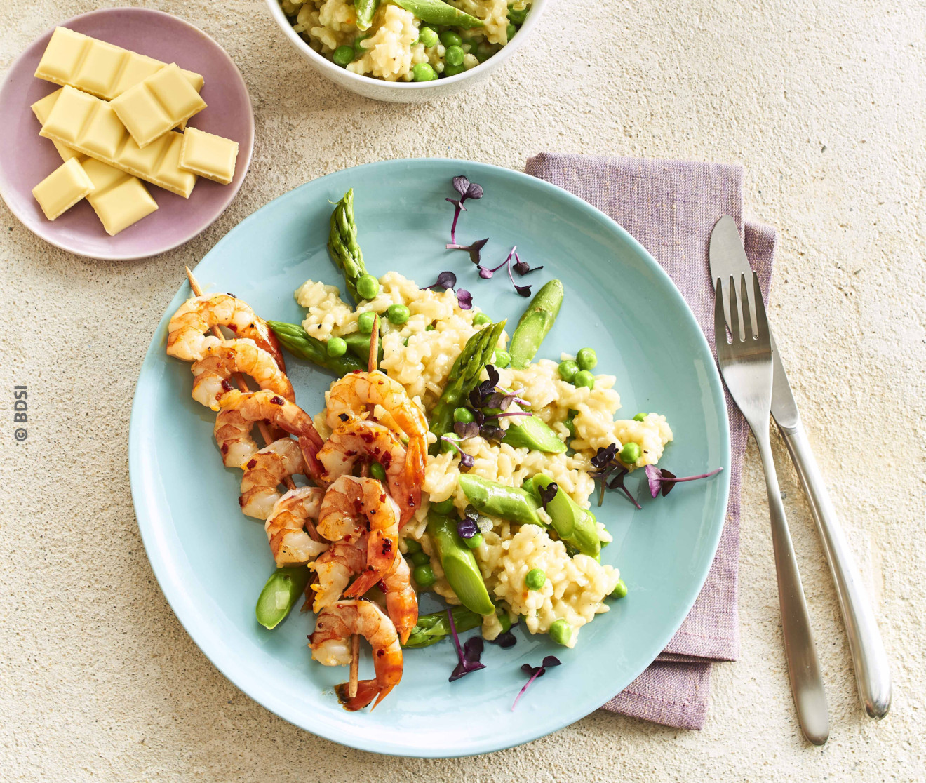 Blick auf ein leckeres frühlingshaftes RIsotto mit grünem Spargel und weißer Schokolade sowie Garnelenspießen.